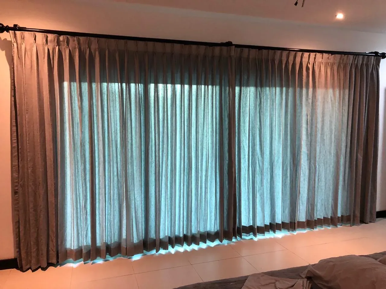 Cortinas plisadas a medida de pared completa con visillo translúcido retroiluminado.