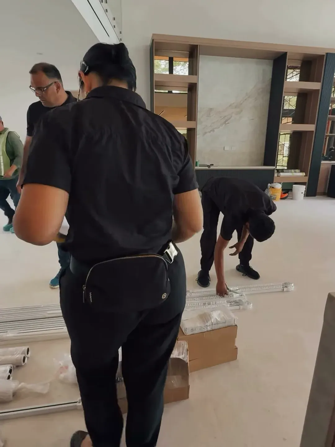 El equipo desembala herrajes y perfiles sobre el piso de una casa en obra.