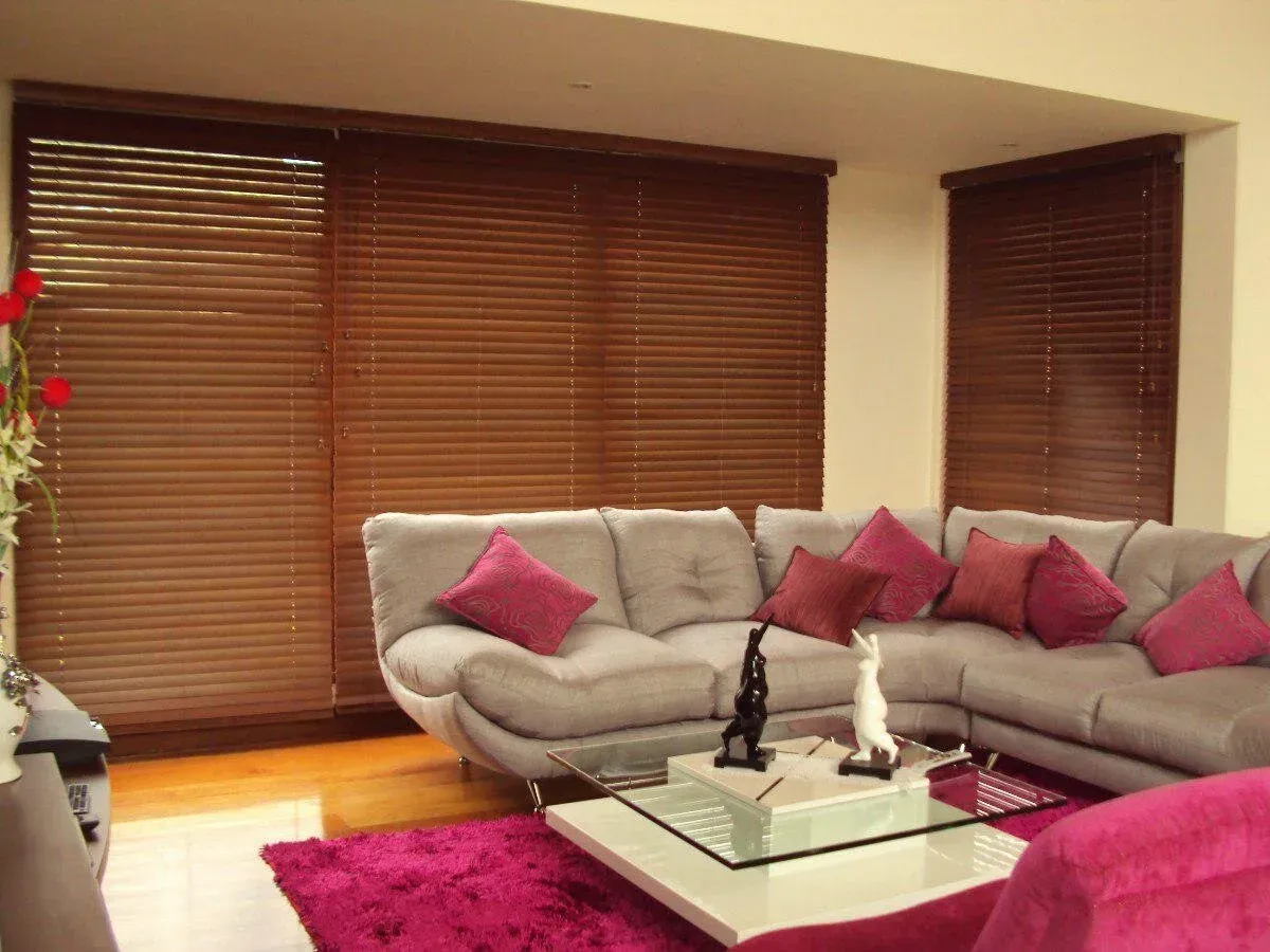 Persianas de madera en sala de estar con muebles oscuros.