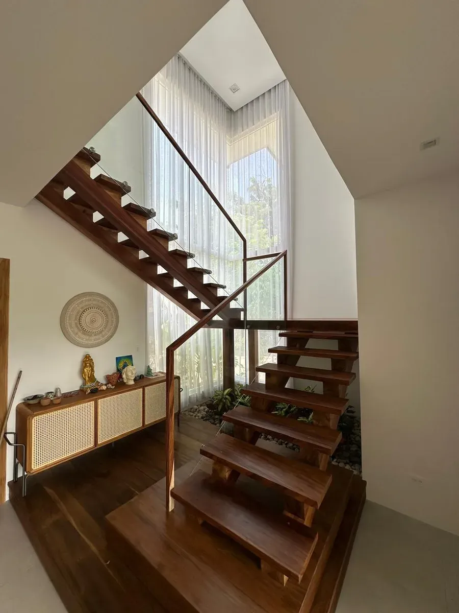 Double-height white sheer drapes alongside a floating wood staircase with a glass railing.