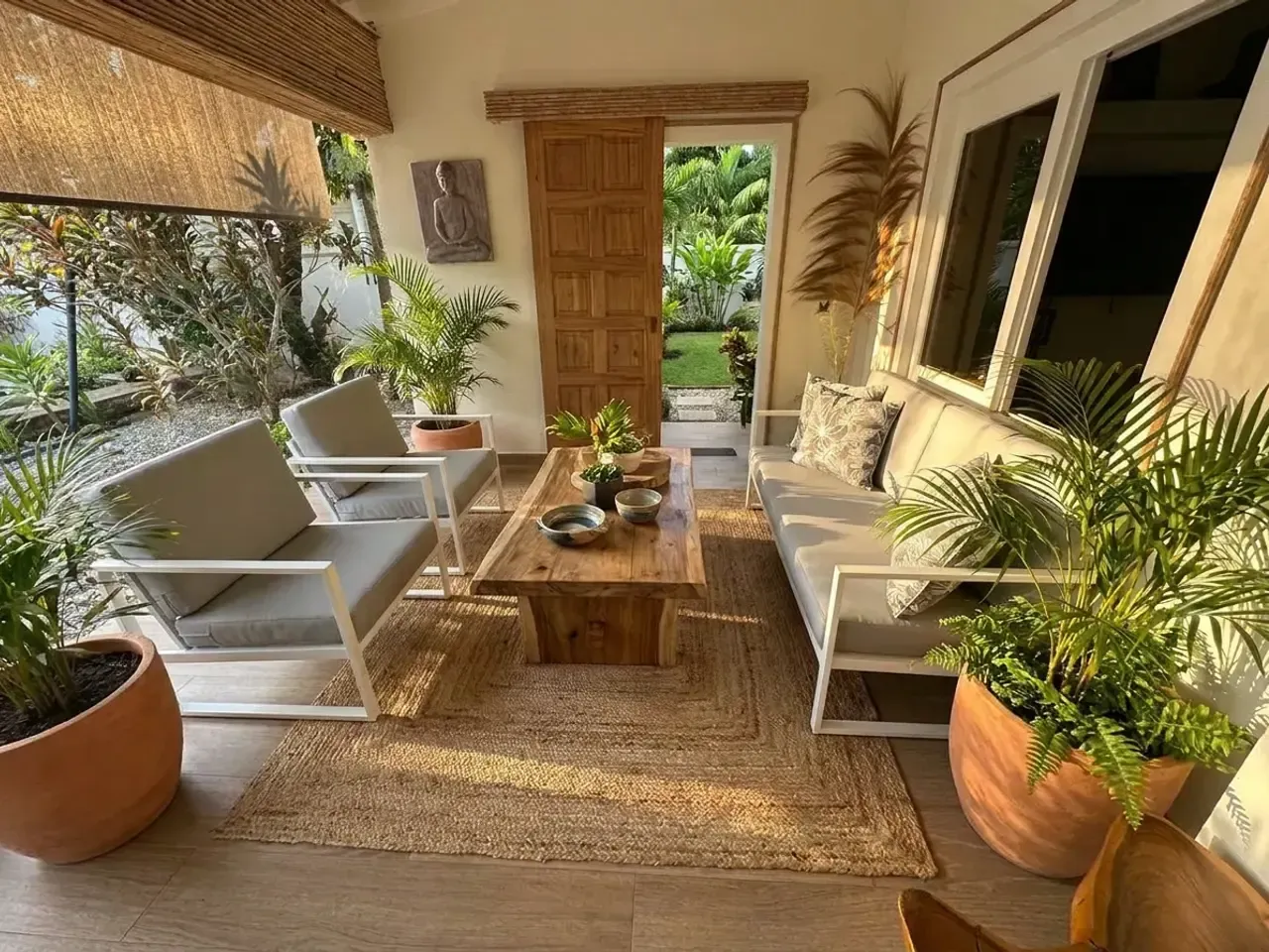 Terraza cubierta con sofá y sillones modulares blancos de cojines beige sobre piso de madera.