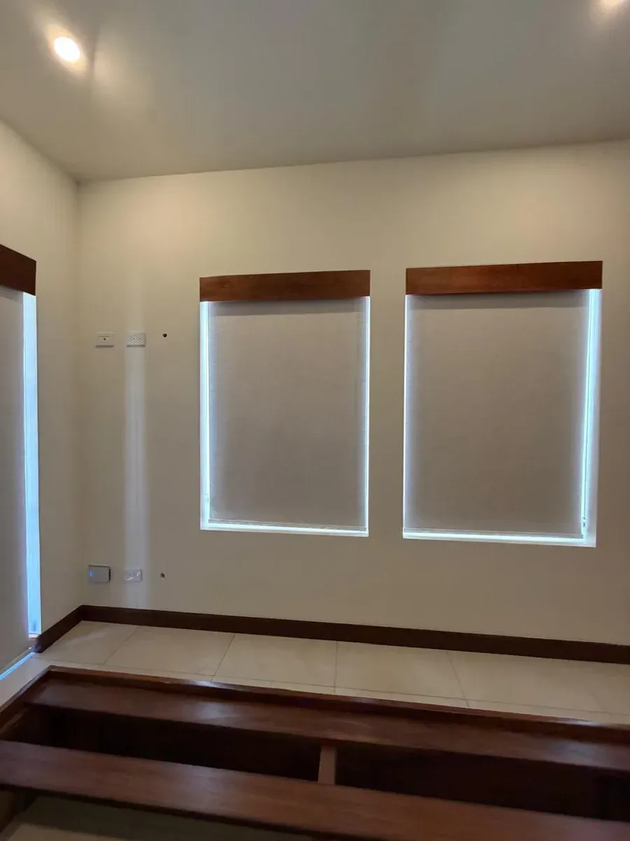 Two cream screen roller shades with dark-wood pelmets across paired windows.