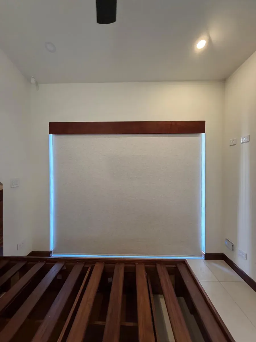 Cream screen roller shade beneath a dark-wood pelmet, above a slatted wood bench.