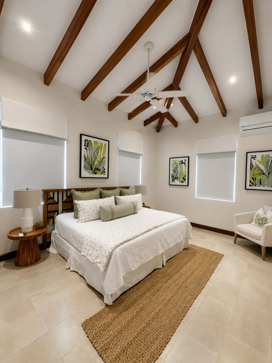 Recámara con techo de vigas y tres cortinas roller blackout recogidas, cama vestida y alfombra de yute.