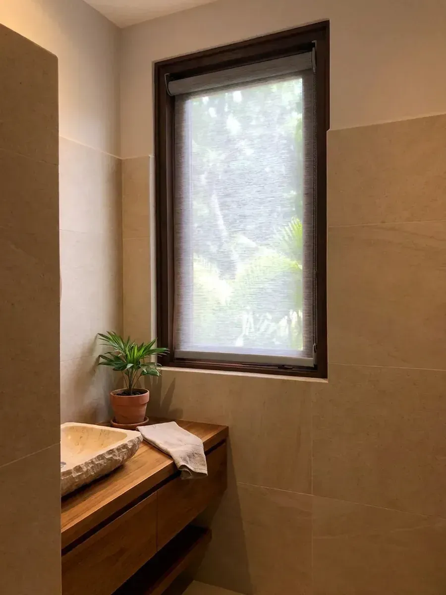 Baño con Sun Screen cubriendo la ventana, mueble de teca con lavatorio de piedra y toallas de lino.